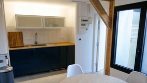 Une cuisine de taille réduite, avec des meubles de couleur sombre, un plan de travail en bois, un évier et une fenêtre donnant sur un paysage agréable.