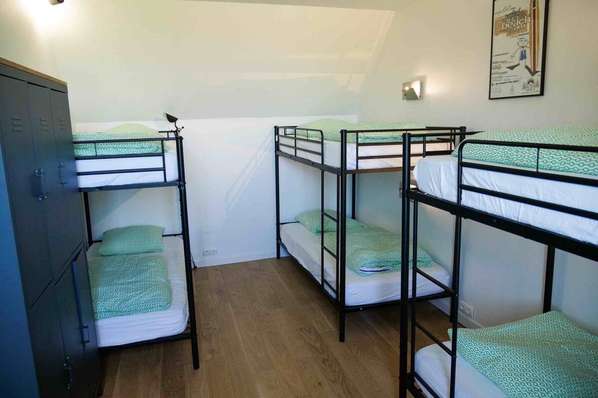 A dormitory room with bunk beds, a wardrobe, and a poster on the wall.