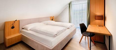 Quarto de hotel moderno com uma cama grande, uma escrivaninha e uma cadeira.