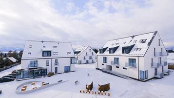 A modern building complex with multiple white structures, large windows, and a snow-covered ground.