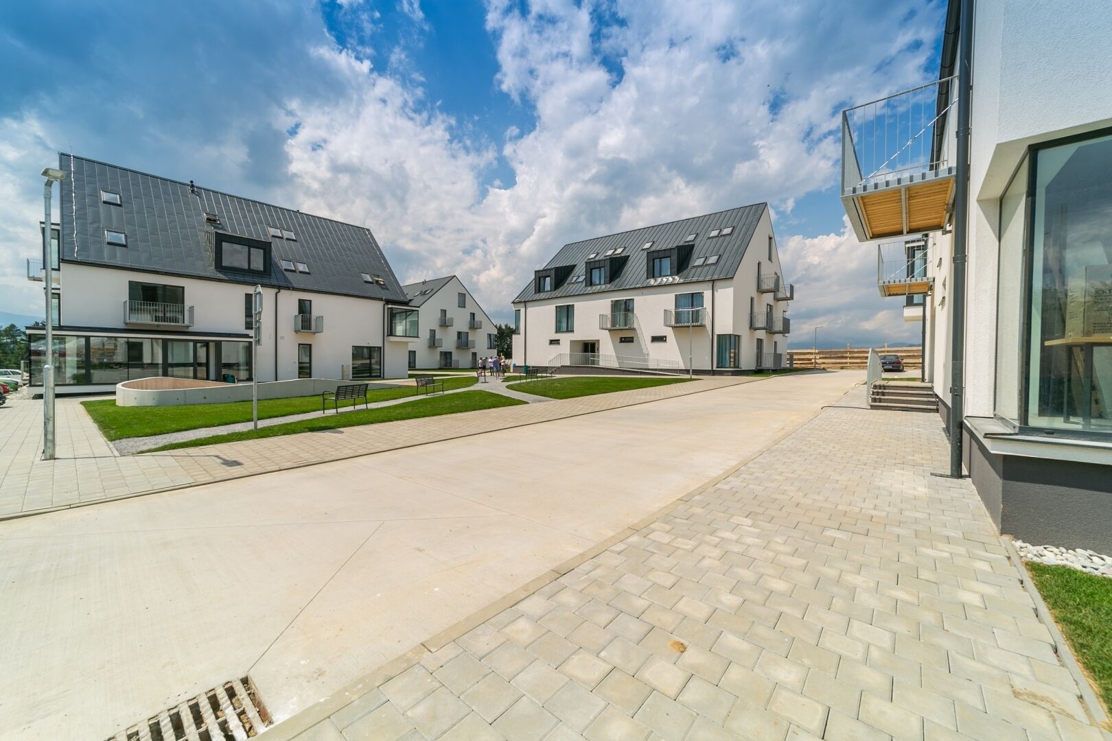 A modern residential complex with multiple two-story houses, a paved walkway, and a grassy area.