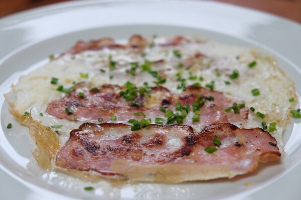 Un plato de comida con jamón a la parrilla y queso derretido sobre un plato blanco.