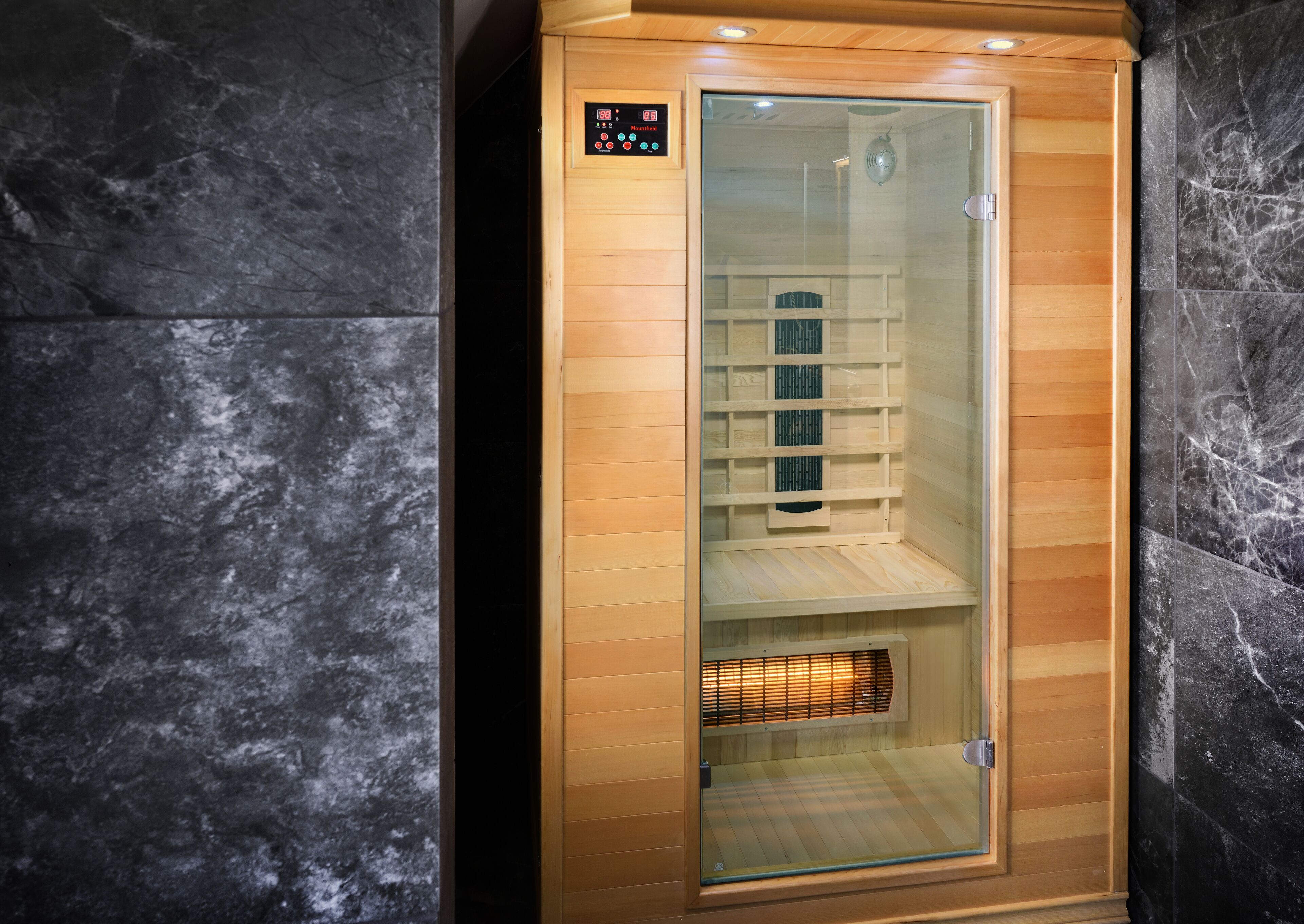 A sauna with a wooden interior, a control panel, and a glass door.