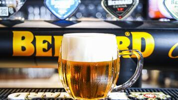 A glass of beer with a frothy head, placed on a bar counter with a beer tap labeled "BEERD" in the background.