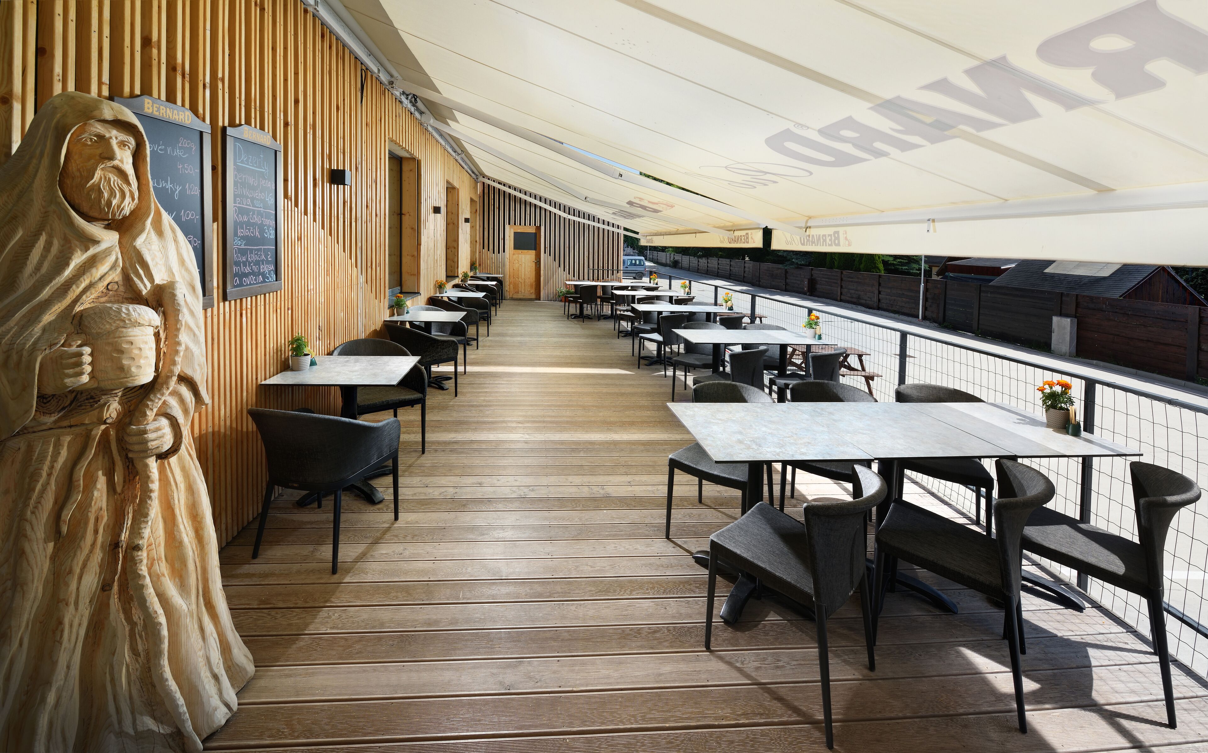 Een restaurant met een lang houten terras, tafels en stoelen.