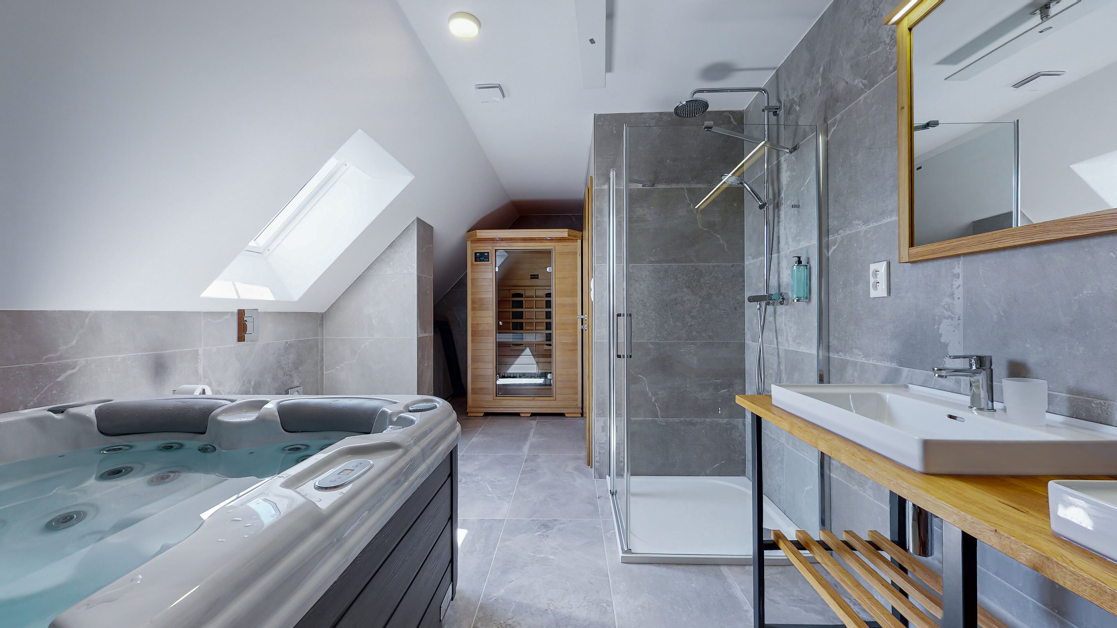 Ein modernes Badezimmer mit einer begehbaren Glasdusche, einer freistehenden Badewanne und einem Waschtisch mit Spiegel.