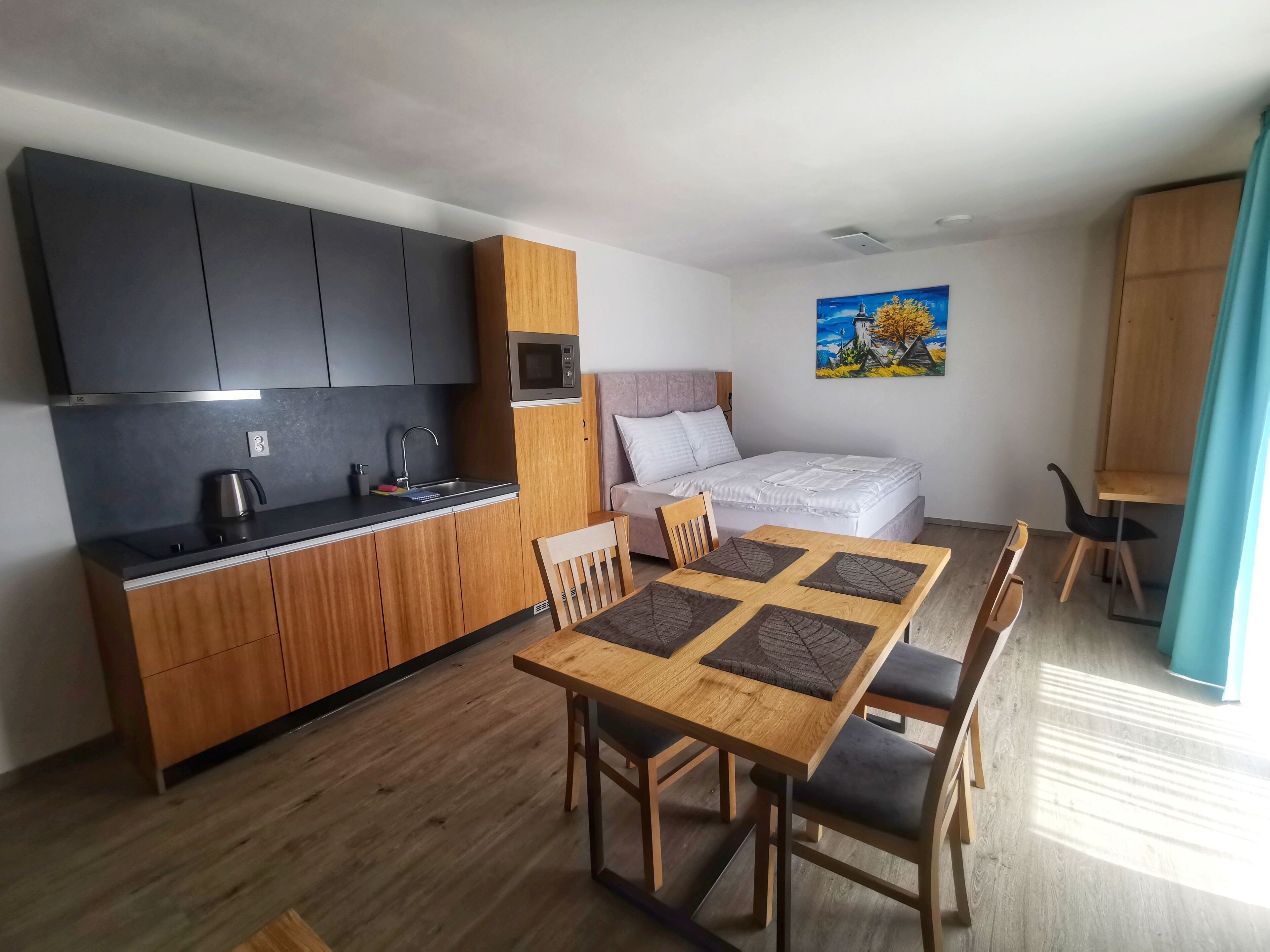 A compact living space with a kitchenette, a dining area, and a bed.