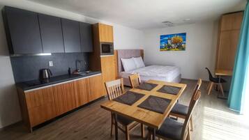 A compact living space with a kitchenette, a dining area, and a bed.