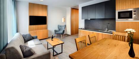 Una sala de estar moderna con un sofá, una mesa de comedor y una zona de cocina con microondas y armarios.
