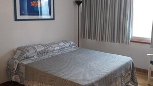A bedroom with a bed, a framed picture, a floor lamp, and a window with curtains. - Villa Pomelia a stone's throw from the sea (Palermo)