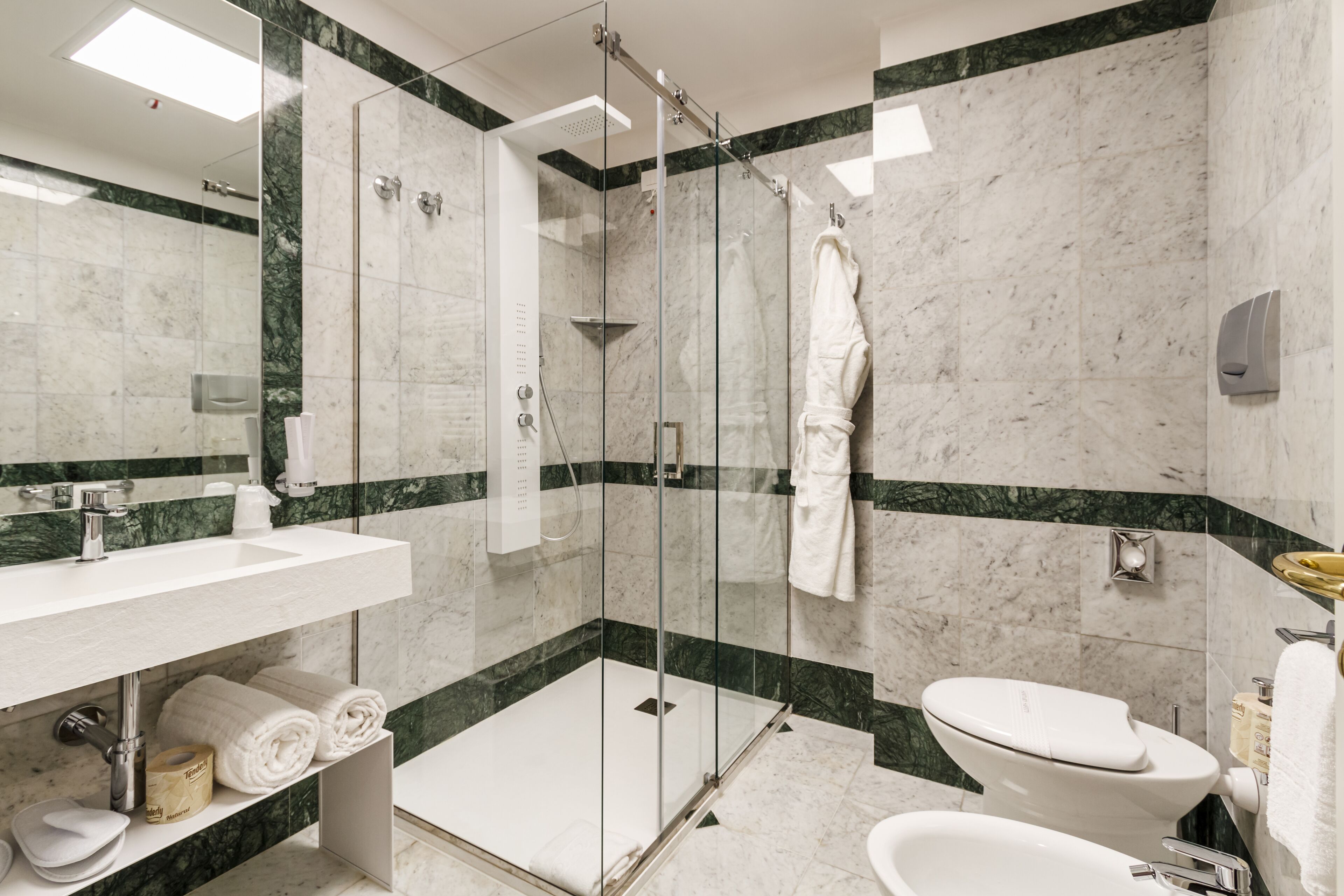 A modern bathroom with a glass-enclosed shower, a white sink, a toilet, and a bathtub.