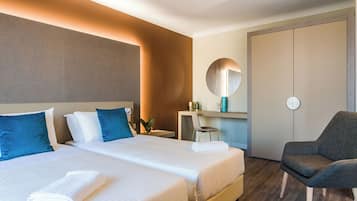 Een hotelkamer met twee bedden, een bureau, een stoel, een spiegel en een kledingkast.