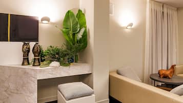 Ein modernes Wohnzimmer mit Marmorplatte, einer Couch, einem kleinen Tisch und Dekorationselementen, darunter Vasen und eine Pflanze.