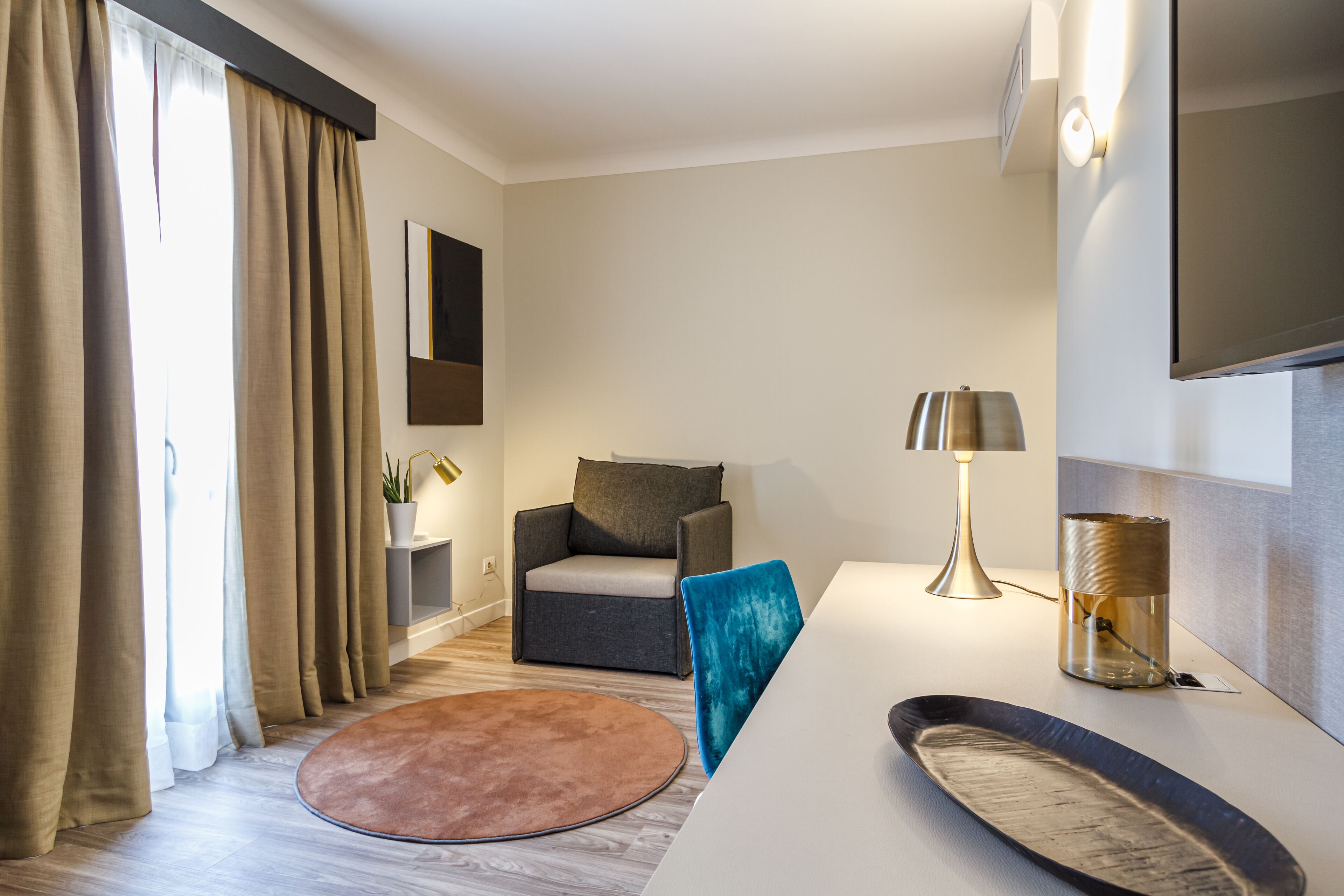 Un salon moderne avec un canapé, une table basse, une lampe et un téléviseur à écran plat fixé au mur.