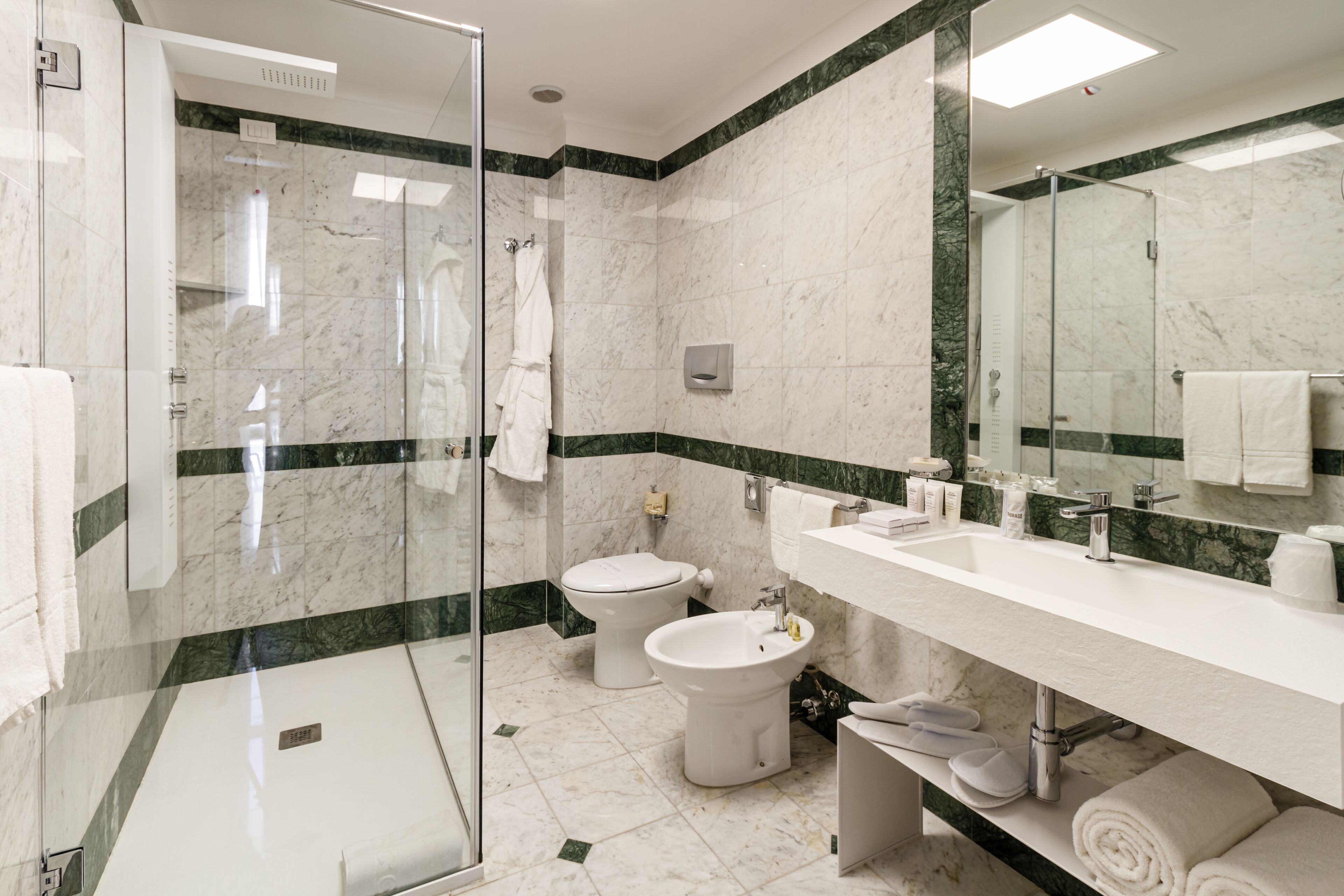 A modern bathroom with a glass-enclosed shower, a white sink, and a bidet.