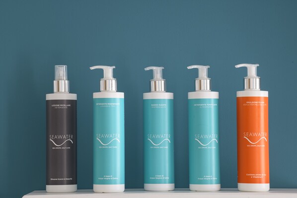 Five bottles of SeaWater products on a shelf against a teal background. - SEAWATER HOTEL BIO & BEAUTY SPA (Marsala)