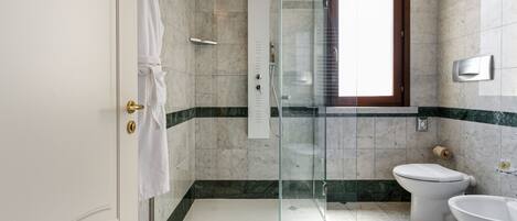 Un baño moderno con ducha envuelta en vidrio, inodoro y lavamanos.