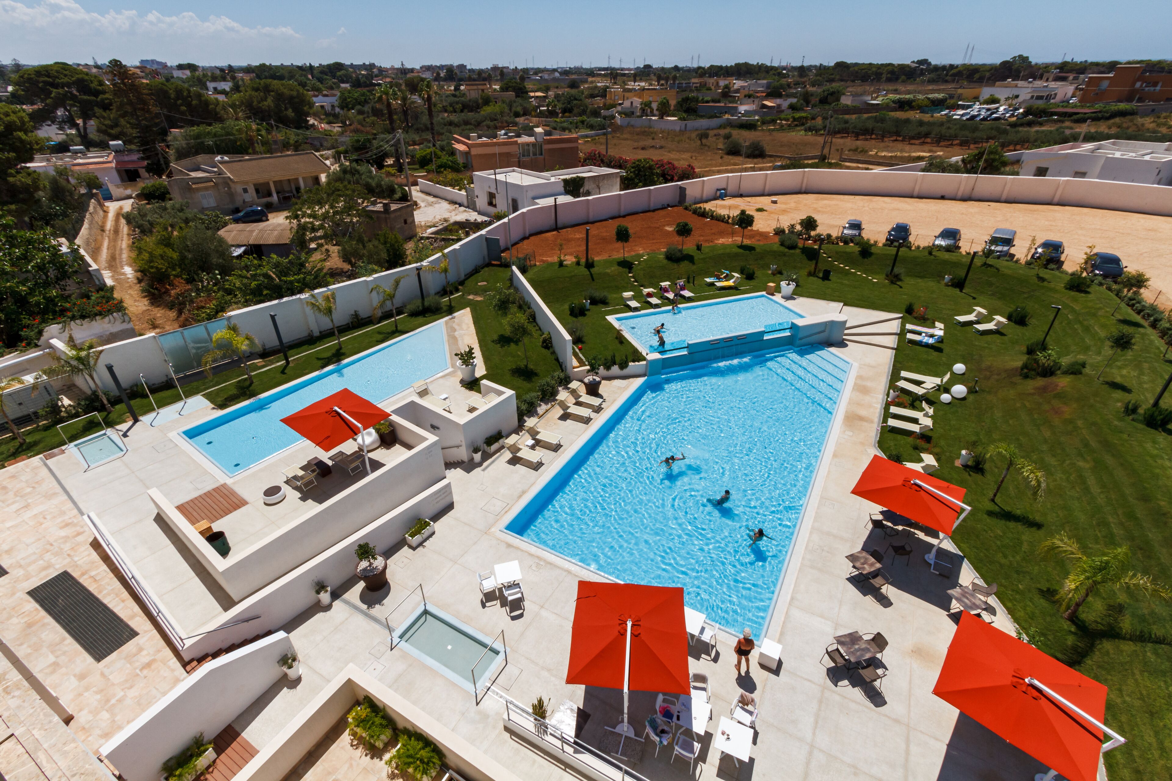 A large outdoor swimming pool with multiple sections, surrounded by lounge chairs and umbrellas.
