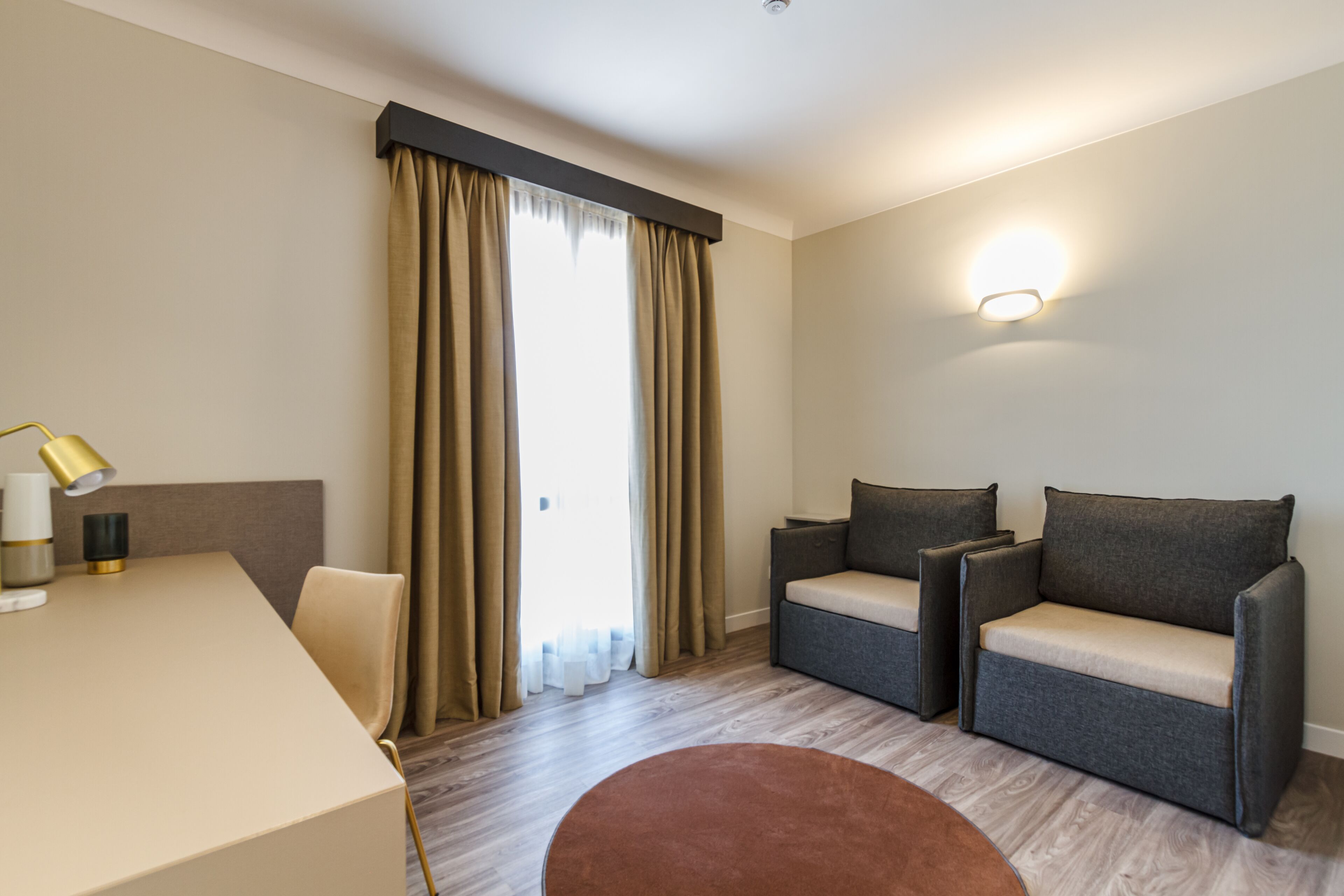 Ein modernes Hotelzimmer mit einer Sofagarnitur, einem Esstisch und einem runden Couchtisch.