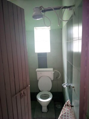 A small, narrow bathroom with a toilet, a window, and a shower head. - Canary Guest House (Matuu)