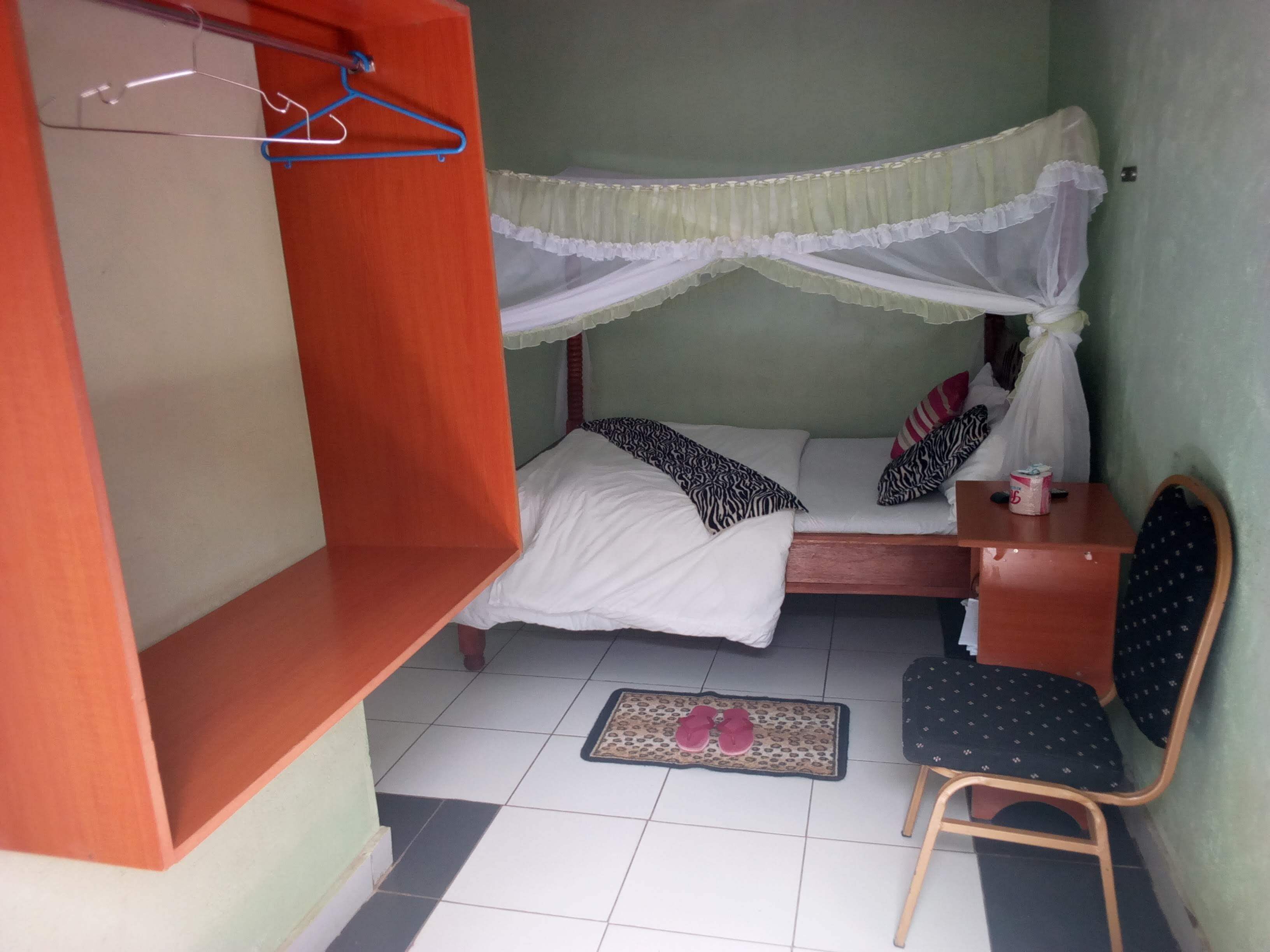 Habitació petita i senzilla amb un llit, una taula i una cadira.