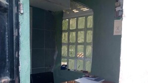 Une pièce avec un bureau en bois, une fenêtre dotée de vitres teintées de vert et une porte partiellement visible.