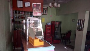 Un petit café avec un comptoir, un réfrigérateur rempli de Coca-Cola et une chaise.