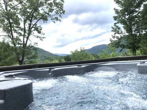 Un bain à remous offrant une vue sur un paysage montagneux et des arbres.