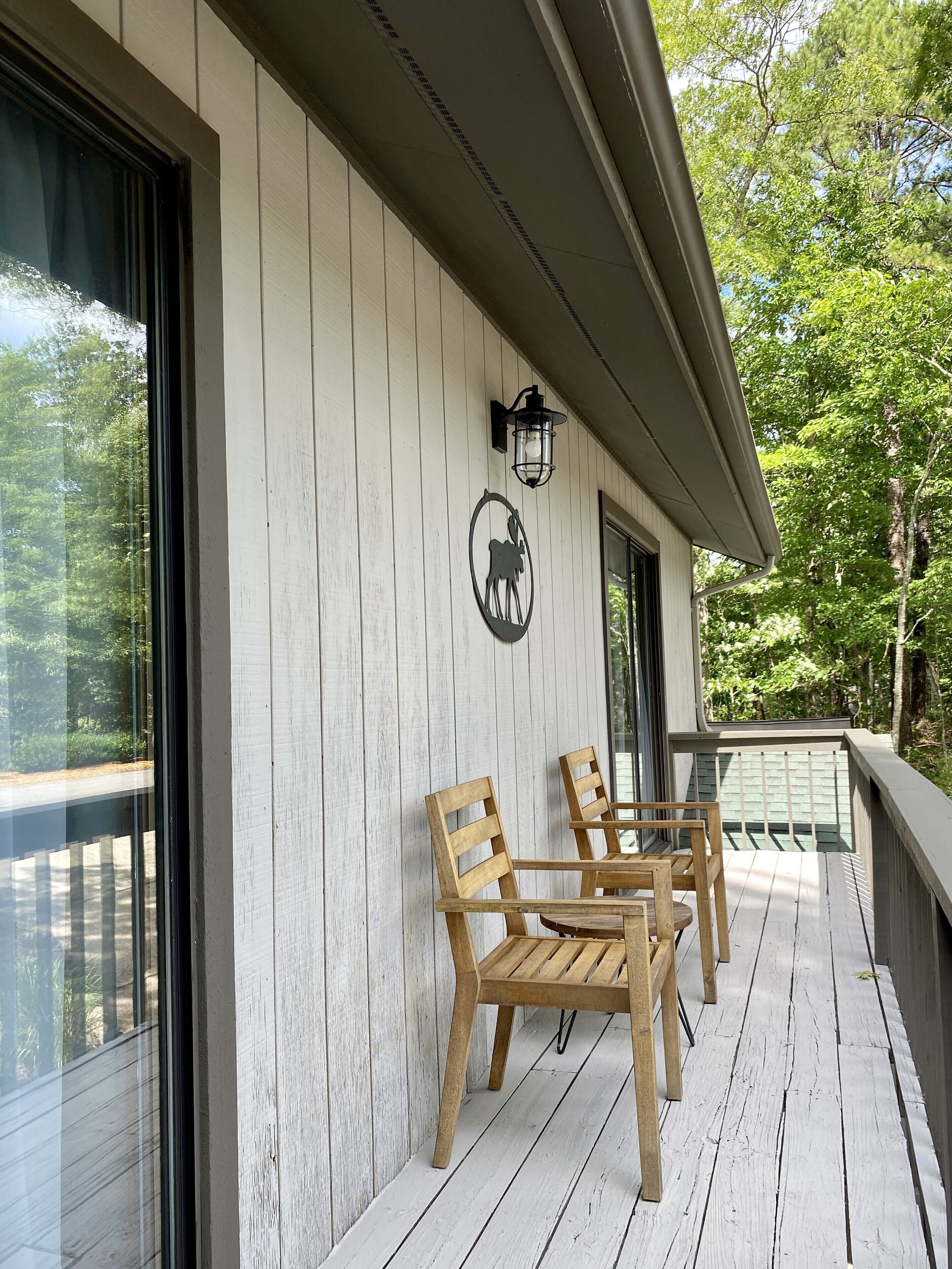 A wooden deck with a table and chairs, a wall-mounted light fixture, and a decorative emblem.