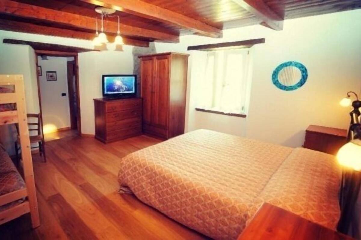 Un dormitorio acogedor con literas, un aparador de madera, un televisor y una ventana con cortinas.