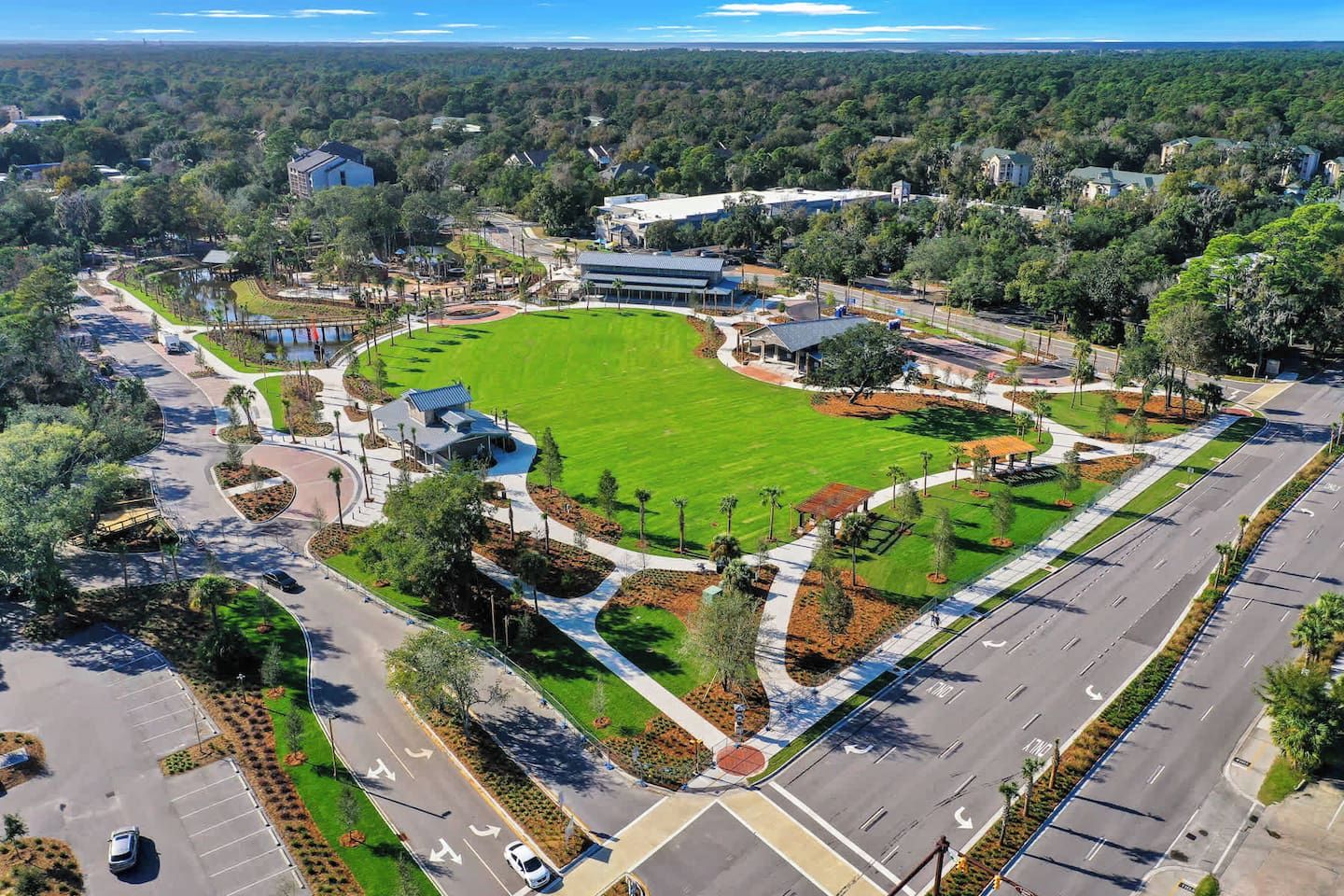 An aerial view of a campus with a central green field, parking areas, and surrounding buildings.