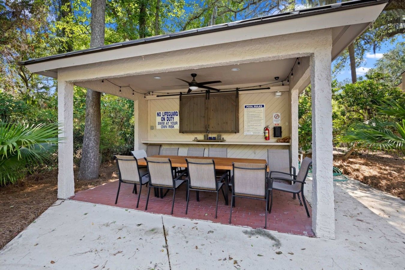 Eine überdachte Terrasse im Freien mit Billardtisch, Stühlen und Deckenventilator.