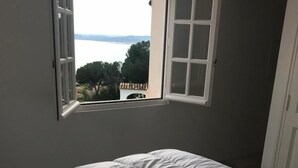 A bedroom with a bed, a window with a view of the sea, and a door. - Large Villa with swimming pool overlooking the golf course of Saint-Tropez (Sainte-Maxime)
