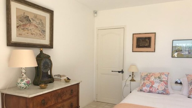 Una camera da letto con un letto, una cassettiera, una porta e due quadri appesi al muro.