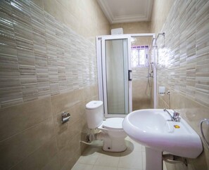 A bathroom with a toilet, a sink, and a shower. - Mays Haven (Taifa)