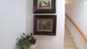 A staircase with a wooden handrail and a white wall with two framed paintings. - Colera Apartment A costa brava (Colera)