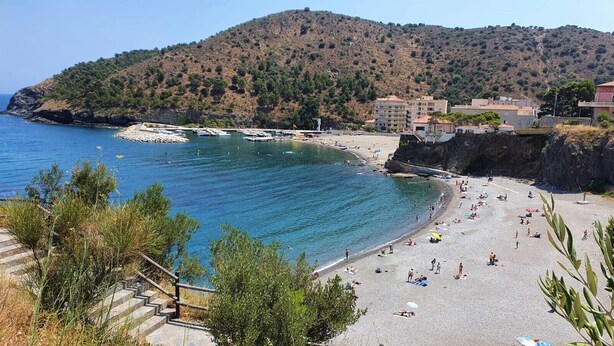 A coastal beach with clear blue waters, a rocky shoreline, and a hilly backdrop. - Colera Apartment A costa brava (Colera)
