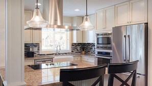 A modern kitchen with stainless steel appliances, a granite countertop, and pendant lighting. - Luxurious Villas in the Blue Ridge Mountains. (Cashiers)