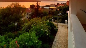 A balcony overlooking a scenic view of a body of water and hills during sunset. - Sea view, 70 m², directly on the sea in Tisno, 2 bedrooms and bathroom (Tisno)