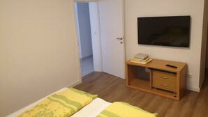 A bedroom with a bed, a TV, a desk, and a door leading to another room. - Sea view, 70 m², directly on the sea in Tisno, 2 bedrooms and bathroom (Tisno)