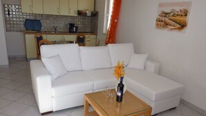 A modern living room with a white sofa, a glass coffee table, and a kitchen in the background. - Sea view, 70 m², directly on the sea in Tisno, 2 bedrooms and bathroom (Tisno)