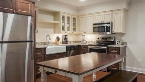 A modern kitchen with stainless steel appliances, a marble countertop, and wooden cabinets. - Historic Patrick Henry Square Resort (Williamsburg)