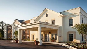 A large, two-story building with a covered entrance and a sign reading "Clearance." - Historic Patrick Henry Square Resort (Williamsburg)