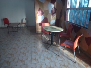 A room with a tiled floor, a round table with chairs, and a window with bars.