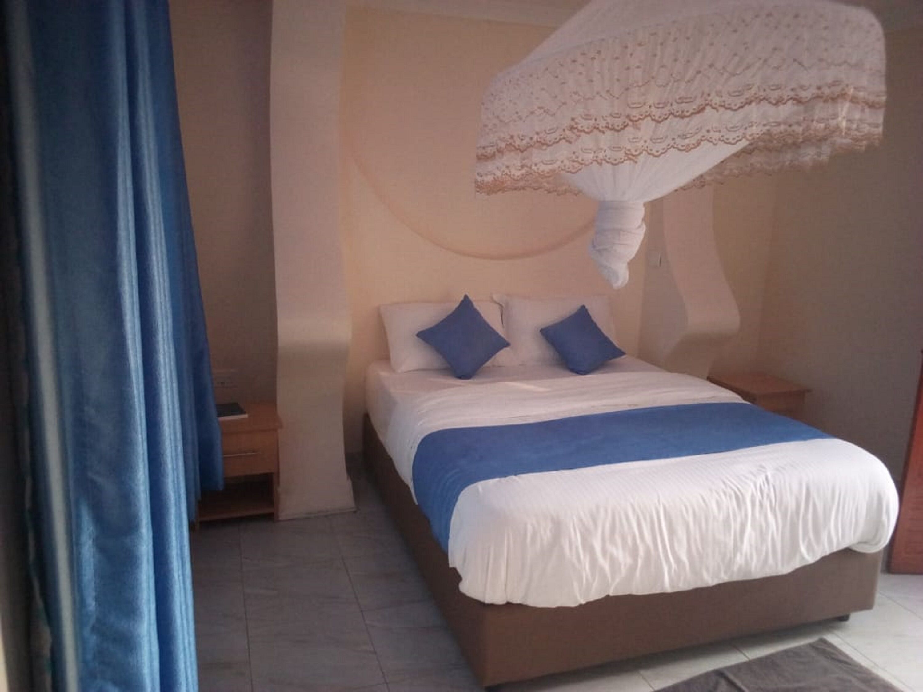 Un dormitorio con cama, almohadas, una mesita de noche y una lámpara colgante.