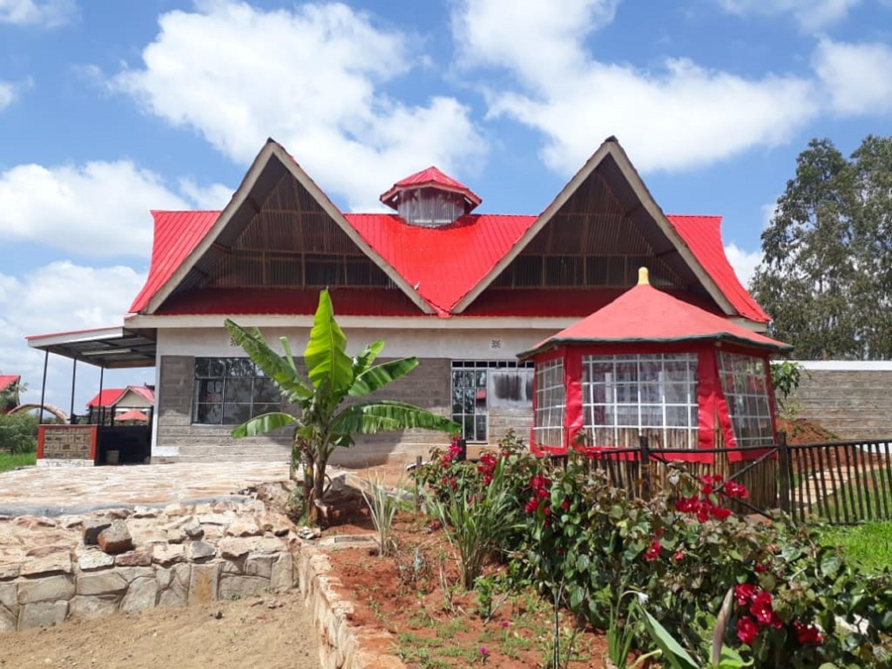 A two-story building with a red roof and a small attached structure with a red roof.
