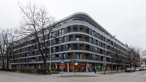 A modern multi-story building with a curved facade, featuring balconies and large windows.