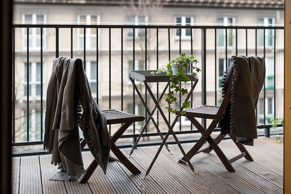 A balcony with two chairs, a small table, and a potted plant.