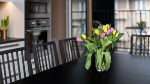 A dining table with a vase of tulips, black chairs, and a kitchen in the background.