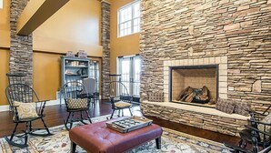 A spacious living room with a stone fireplace, comfortable seating, and a bookshelf. - Shenandoah Crossing Resort with acres of wilderness (Gordonsville)